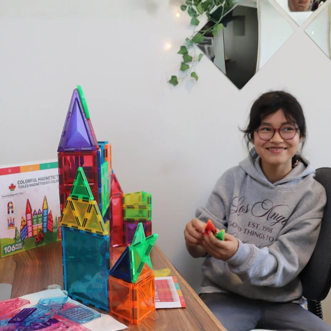 Child playing with Tessella Master Set – 106 Piece Magnetic Tiles, building a tall colorful tower on a table, STEM educational toy for kids ages 3+, compatible with Connetix, PicassoTiles, Magna-Tiles.